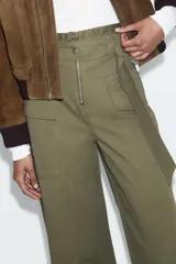Pantalón de tiro alto con diseño paperbag, pernera ancha y cierre frontal con cremallera. Cuenta con bolsillos laterales de plastrón con solapa y cintura con trabillas.