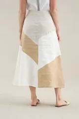Falda larga de lino con diseño de cortes diagonales en bloques de color blanco, beige y tostado, de corte evasé y caída fluida.