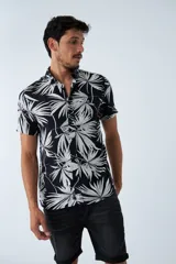 Camisa de manga corta con estampado botánico de hojas en tonos azul y blanco. Presenta cuello clásico, cierre frontal abotonado y corte slim.