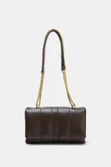 Mini bandolera de efecto acolchado en color marrón oscuro, con diseño de pespuntes verticales. Cuenta con una cadena dorada que funciona como asa de hombro o bandolera, cierre de solapa con botón imantado y doble compartimento interior con bolsillo con cremallera.