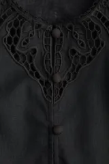 Vestido corto negro, tipo túnica, confeccionado en mezcla de lino y algodón. Presenta inserciones de encaje calado en el canesú y volados superpuestos en el frente y hombros. Tiene escote redondo, cierre frontal con botones forrados y mangas largas con puños finos abotonados.