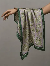 Pañuelo cuadrado de satén con estampado floral sobre fondo verde y lila, con bordes en tono verde oscuro.