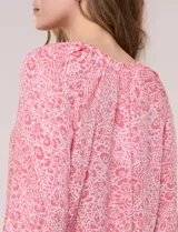 Blusa holgada de gasa liviana con estampado floral en tonos rosados y blancos. Presenta escote en V con muesca central y mangas largas abullonadas con inserción de puntilla y puños elastizados.