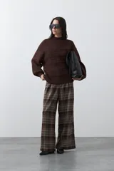 Sweater de punto color marrón chocolate, con cuello redondo, mangas largas abullonadas y puños ajustados. Presenta un diseño de textura acanalada horizontal y silueta relajada.
