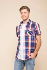 Camisa de manga corta con estampado de cuadros en tonos verdes, azules y blancos. Presenta cuello clásico, cierre frontal con botones y dos bolsillos delanteros con solapa.