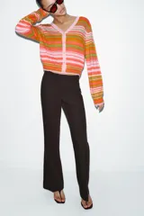 Chaqueta de punto con cuello pico y manga larga, con cierre frontal de botones. Presenta un estampado de rayas horizontales en tonos rosado, naranja y verde.