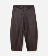 Pantalón de cuero sintético con corte barrel, de tiro alto y pierna ancha con estructura curva. Presenta bolsillos laterales tipo cuchillo y costuras decorativas con pespuntes visibles.