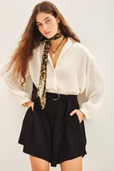 Short negro de tiro alto con pliegues y cinturón con hebilla metálica. El tejido presenta un sutil estampado jacquard.