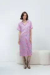 Vestido midi con estampado de figuras geométricas en tonos rosado y azul, con cuello camisero y mangas cortas.