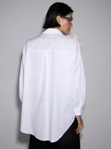 Camisa blanca de mangas largas con apliques de flores blancas y lazos negros.