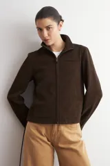 Chaqueta de cuero color marrón oscuro, con cuello alto, cierre frontal y diseño minimalista de corte recto.