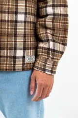 Camisa leñadora marrón a cuadros con forro de corderito sintético, cierre con botones y dos bolsillos frontales con tapa.