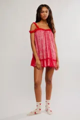 Vestido corto de tul bordado color rojo y rosado, con escote recto, volados sobre los hombros, tiras finas regulables y ruedo terminado en volado. Caída suelta y liviana.