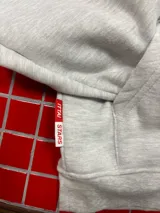 Buzo con capucha gris jaspeado, de corte holgado, con estampado gráfico en la espalda que incluye el texto 'Ittai Company' y una figura de un animal en color rojo.