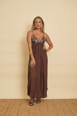 Vestido largo marrón con tirantes finos, escote en V y corte imperio. El corpiño está decorado con lentejuelas brillantes y la falda larga presenta líneas de abalorios y detalles bordados en vertical.