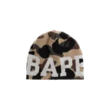 Gorro beanie de punto con patrón de camuflaje en tonos marrones, negros y beige, con la palabra "BAPE" estampada en letras grandes blancas en la parte frontal.