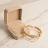 Pulsera de plata 925 con baño de oro, compuesta por una banda de malla metálica y una doble cadena fina colgante. Presenta un dije central en forma de corazón pavé con circonias.
