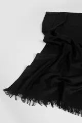 Pashmina ligera de color negro con textura lisa y terminaciones de flecos en los extremos.