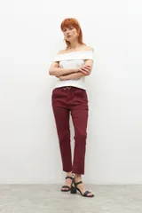 Pantalón de vestir color bordó, de corte recto, con bolsillos laterales y traseros. Se ajusta a la cintura con cinturón de cuero marrón.