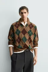Polo de punto de corte relajado, con estampado de rombos en tonos marrón y verde. Presenta cuello solapa con abertura frontal, manga larga y acabados en rib.