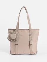 Bolso tipo shopper color verde oliva, confeccionado en poliéster con acabado satinado. Presenta doble asa de hombro, detalles de argollas metálicas frontales y un pequeño monedero circular removible con cierre.