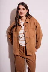 Sobrecamisa de mujer color camel, con textura de gamuza, cuello camisero, botones frontales y bolsillos de parche en el pecho. Presenta un calce oversize.