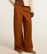 Pantalón pantalona de tiro alto en color marrón, confeccionado en sarga. Cuenta con corte amplio y viene acompañado de un cinturón con hebilla redondeada.