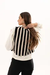 Chaleco tejido a rayas verticales en color negro y crudo, con escote en V y cierre frontal con ganchitos.