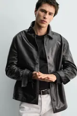 Sobrecamisa de corte regular confeccionada en piel napa negra, con cuello solapa, cierre frontal de botones y mangas largas con puños abotonados.