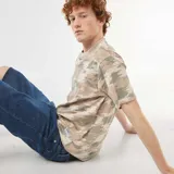 Remera de algodón con cuello redondo y estampado de camuflaje en tonos verde militar, beige y marrón, de corte relajado y mangas cortas.