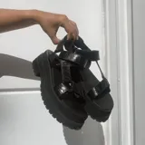 Sandalias negras de plataforma con suela track y tiras ajustables con textura efecto cocodrilo.