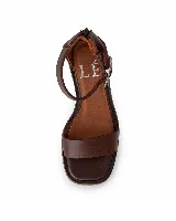 Sandalia de cuero color beige con punta cuadrada, taco ancho efecto madera y tira en el tobillo con hebilla ajustable.