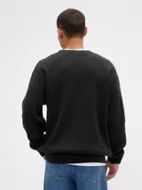 Buzo de tejido acanalado con cuello redondo, mangas largas y puños ajustados. Diseño de corte clásico y textura marcada.