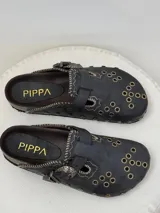 Zuecos de cuero marrón con diseño vintage, tachas plateadas y hebilla lateral.