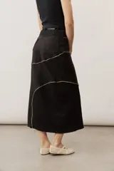Pollera midi de corte recto, color negro, con costuras curvas decorativas en tono tostado y un panel lateral de encaje.