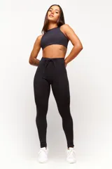 Calza deportiva negra de tiro alto, confeccionada en poliamida con elastano, con costuras laterales visibles y cordón ajustable en la cintura.