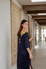 Vestido largo azul con cuello con apliques de cuero y flecos en el ruedo.