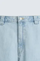 Shorts de denim de algodón, color celeste lavado, de corte regular fit y largo hasta la rodilla. Presenta cierre frontal con cremallera y botón, bolsillos delanteros y bolsillos traseros de plastrón. El borde inferior tiene un acabado deshilachado.