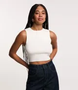 Blusa tipo musculosa cropped, ajustada al cuerpo, de color blanco y textura acanalada.