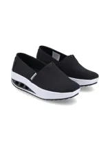 Zapatillas tipo slip-on Hush Puppies modelo Angelo, color negro, confeccionadas en tela canvas con elástico en el empeine para un calce sencillo. Poseen una suela de plataforma con tecnología de amortiguación y plantilla de memory foam de alta densidad.