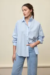 Camisa celeste de corte oversize, con mangas largas, cuello camisero y cierre frontal de botones.