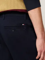 Pantalón chino Tommy Hilfiger modelo Denton de pierna recta, color azul marino, confeccionado en satén de algodón elástico. Cuenta con cierre de cremallera y botón, bolsillos ribeteados en la cintura y bolsillos traseros de ojal con botón.