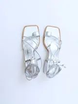 Sandalias plateadas con tiras finas y tacón cuadrado.