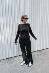 Jean wide leg color negro, de tiro medio-alto, con costuras verticales frontales y tajos en el ruedo.