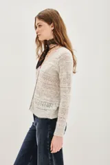 Cardigan de punto calado en color beige, con escote en V y cierre frontal de botones. Presenta un diseño de textura con franjas horizontales y mangas largas.