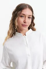 Camisa de manga larga color blanco, con cuello mao y corte holgado. Confeccionada en tejido tipo lino.