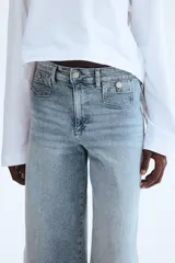 Jean tobillero de denim de algodón con leve stretch, piernas amplias, tiro alto, bolsillos parche delanteros con botón y corte holgado de muslo a bajo.