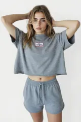 Remera gris de corte cropped con cuello redondo y manga corta. Estampado rectangular en el pecho con texto "Western Avenue Champions".