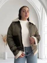 Chaqueta gamulan color verde con interior de piel sintética blanca, cierre frontal con cremallera y detalles en cuero marrón.