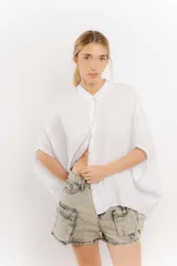 Camisa blanca de lino con mangas amplias y cinta en tono más oscuro en cuello y abotonadura.